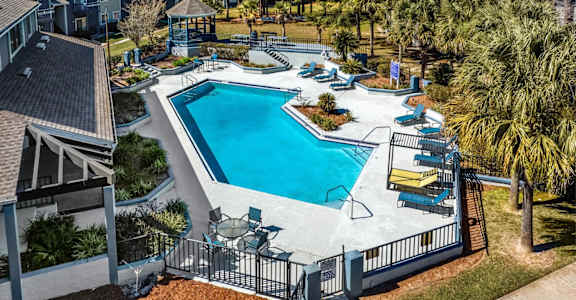 A swimming pool surrounded by a fence and chairs.