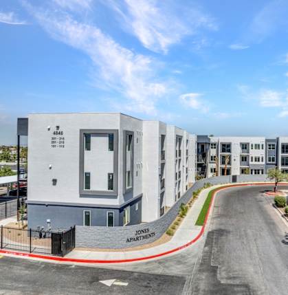 A street view of a residential area with apartment buildings and a clear sky.