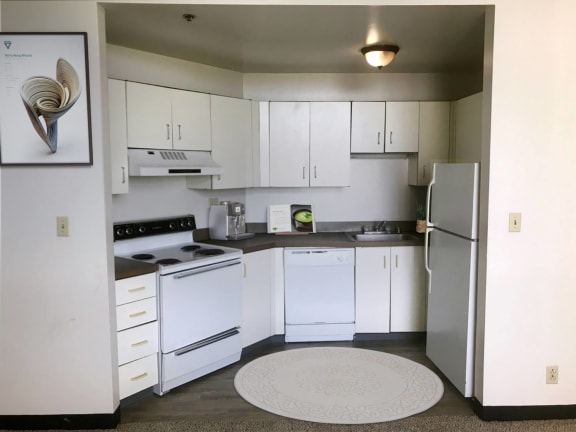 a kitchen with white appliances and white cabinets at Delmar Loop Apartments, Missouri