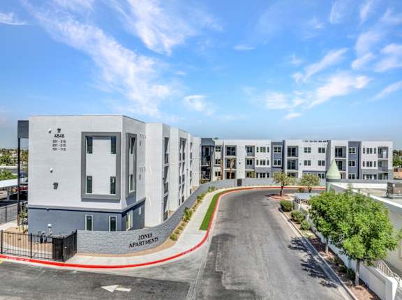 A street view of a residential area with apartment buildings and a clear sky.