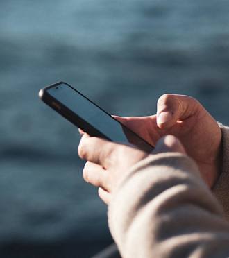 A person's hand holding a smartphone with a black screen.