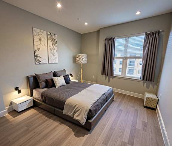 A bedroom with a large bed and a window with curtains.