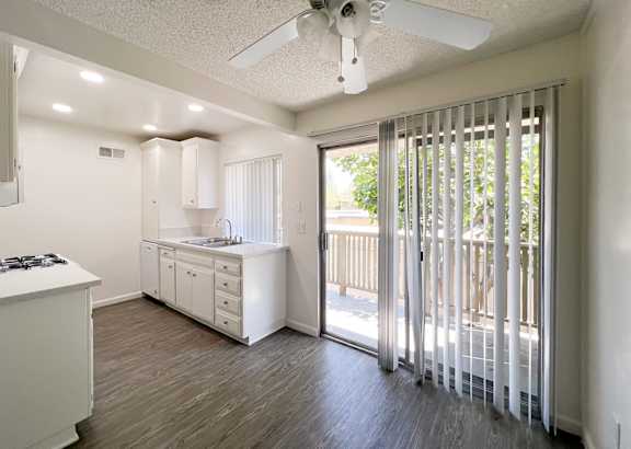 A white kitchen with a fan and sliding glass doors.