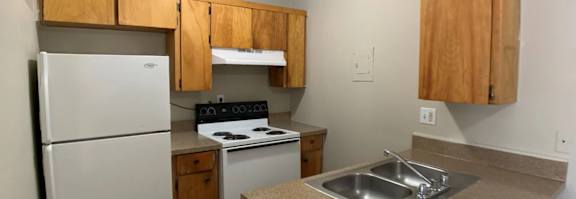 A kitchen with a refrigerator, oven, and microwave.