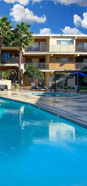 A swimming pool in front of a multi-story apartment building.