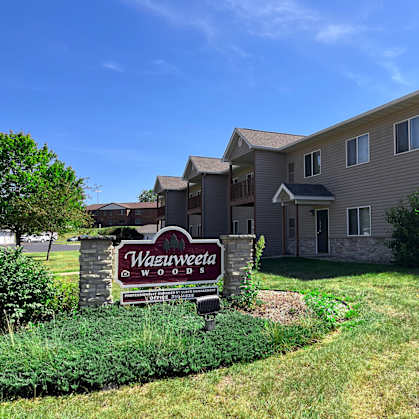 A sign in front of a building that says Wazweeta Woods.
