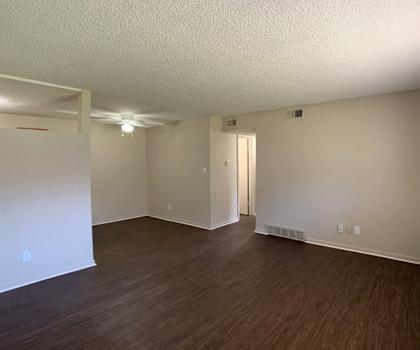 A room with wooden flooring and a door in the middle.