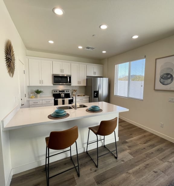 a kitchen with a white counter top and a island with two chairs