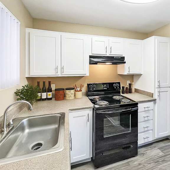 A kitchen with a black stove top oven and white cabinets.