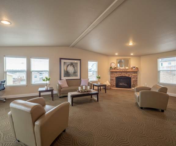 The resident lounge with a fireplace, windows, couches, plush chairs, and coffee tables at Four Seasons. 