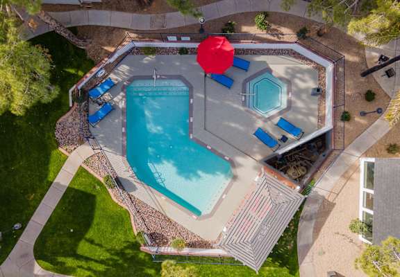arial view of a swimming pool with a red umbrella in the middle