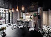 Thumbnail 5 of 8 - A modern dining area with a black table and chairs, and people standing in the background.