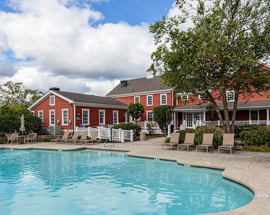 A red house with a pool in front.