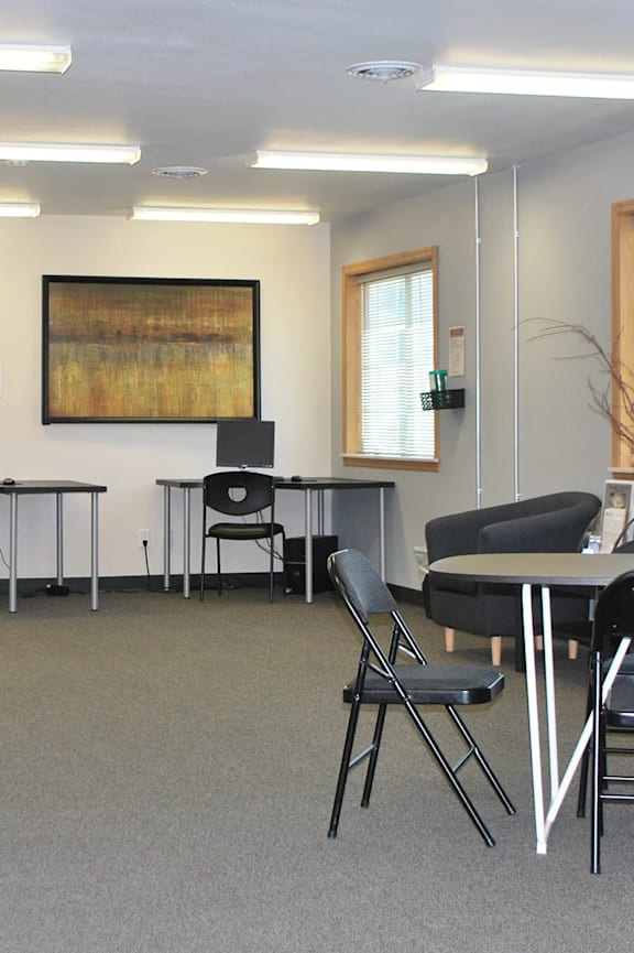 A conference room with a grey carpet and black chairs.