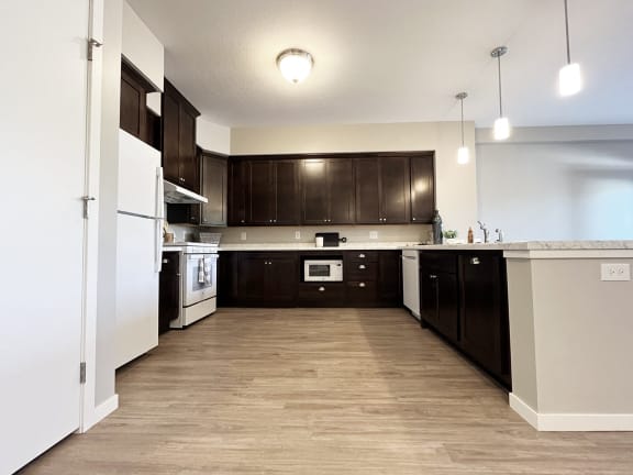 an empty kitchen with dark wood cabinets and white appliances
