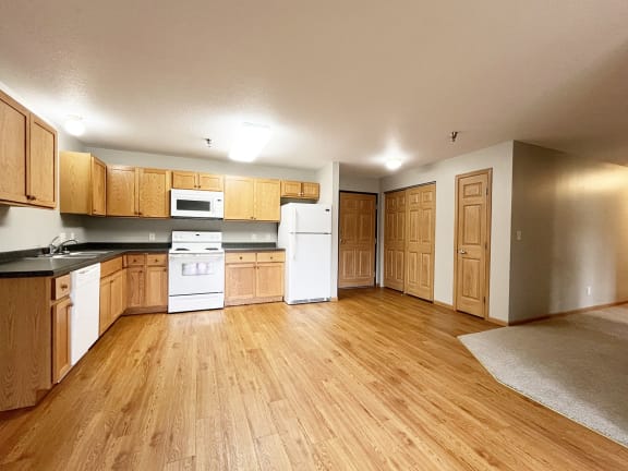 an empty kitchen with wooden floors and white appliances