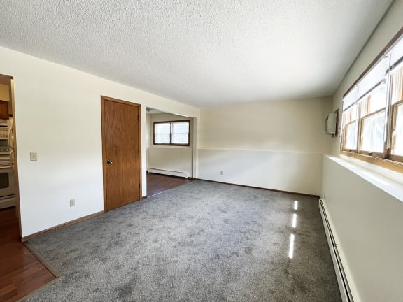 an empty living room with white walls and a wooden door
