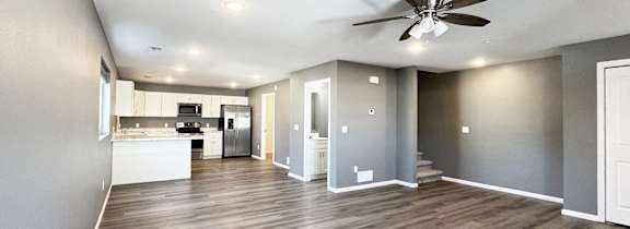 A spacious room with a ceiling fan and wooden flooring.