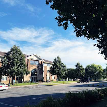A parking lot in front of a building with trees and a clear sky.