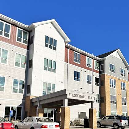 an exterior view of a multifamily apartment building with cars parked outside