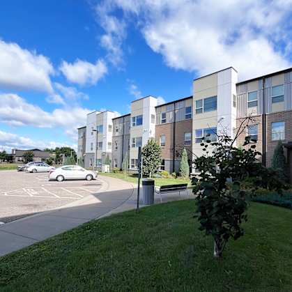 A modern apartment complex with a parking lot in front.