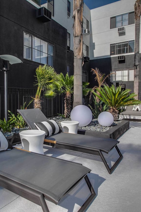 a patio with lounge chairs next to a pool