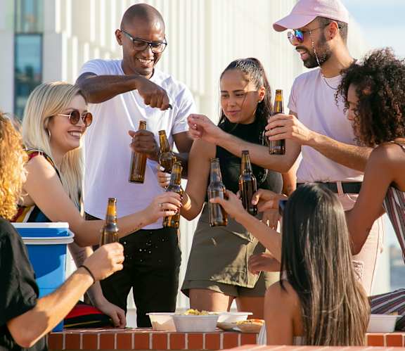 a group of people standing around a table drinking beer