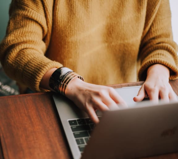 a woman using a laptop computer on a wooden desk