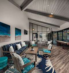 A modern living room with a blue and white rug, a wooden sofa, and a painting on the wall.