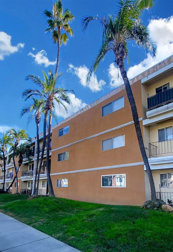 A building with a balcony and a palm tree in front of it.