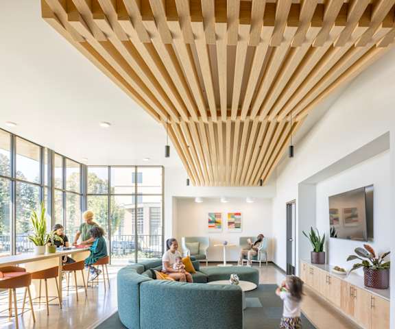 A woman and two children are sitting on a couch in a room with a wooden ceiling.