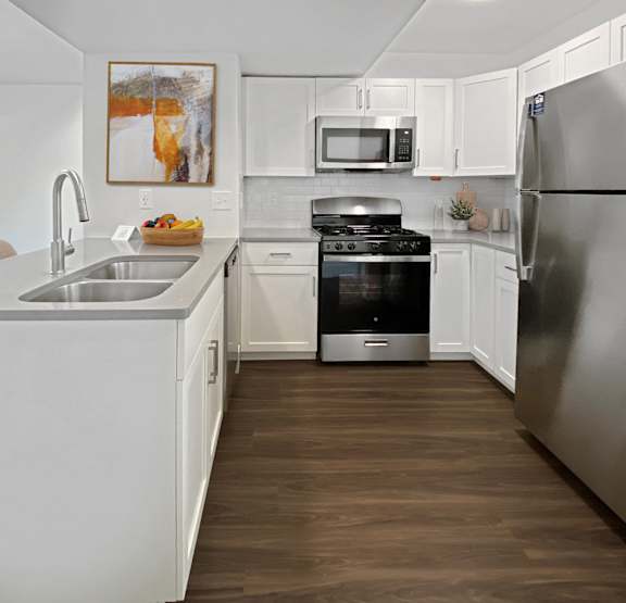 a kitchen with white cabinets and stainless steel appliances at Byron Lakes Apartments, Byron Center