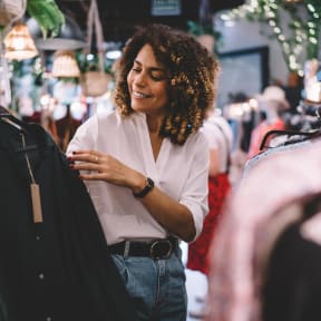 a woman looking at clothes on a rack in a clothing store