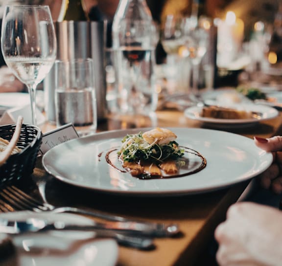 A family is gathered around a dinner table with lit candles.