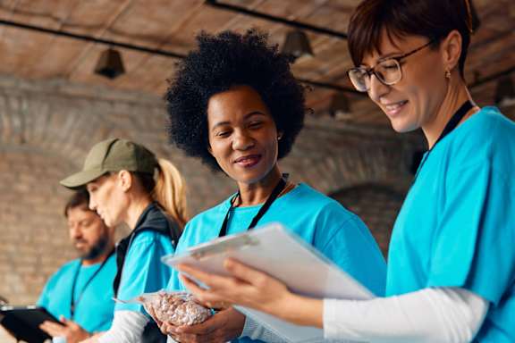 A group of people in blue shirts are serving food to others.