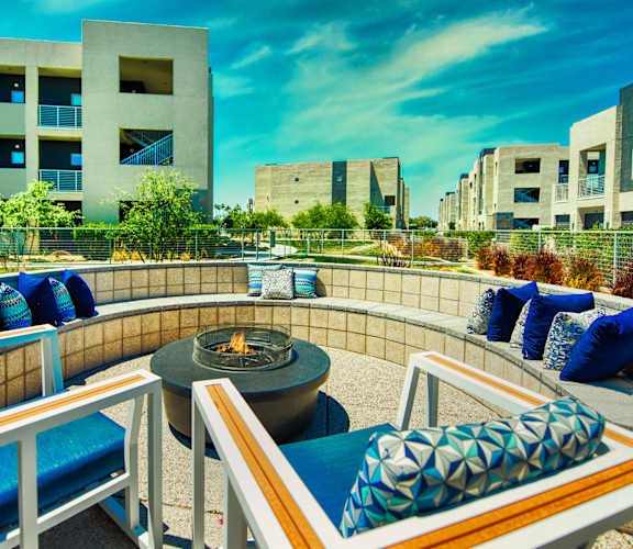 A patio with a fire pit and chairs with blue cushions.at Craft at Gilbert and Baseline, Mesa, AZ 85204