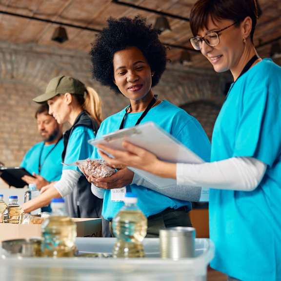 A group of people in blue shirts are serving food to others.