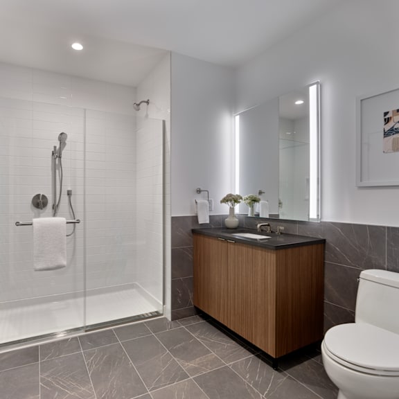 A modern bathroom with a wooden vanity and a white toilet.