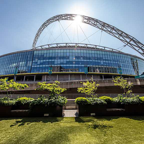 The sun shines brightly on the exterior of a modern stadium.