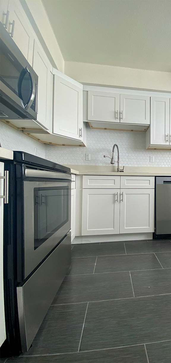 A kitchen with white cabinets and a black fridge.