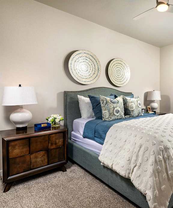 A bedroom with a bed, nightstand, and two wall hangings.