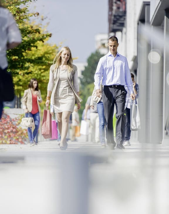 a man and woman walking down the street with shopping bags