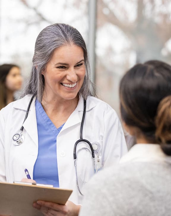 a woman physician smiling and talking to a group of patients
