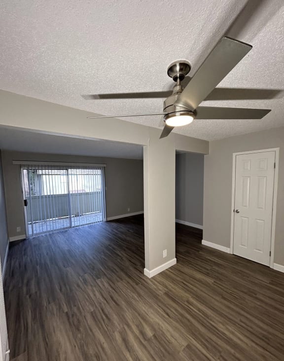 an empty living room with wood flooring and a ceiling fan