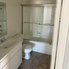 A white bathroom with a toilet, sink, and shower.