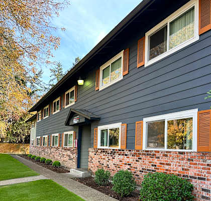 A house with a grey siding and a brick wall.