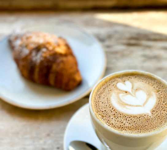 a cup of coffee and a croissant on a table