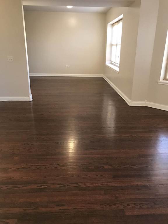an empty living room with wooden floors and a window