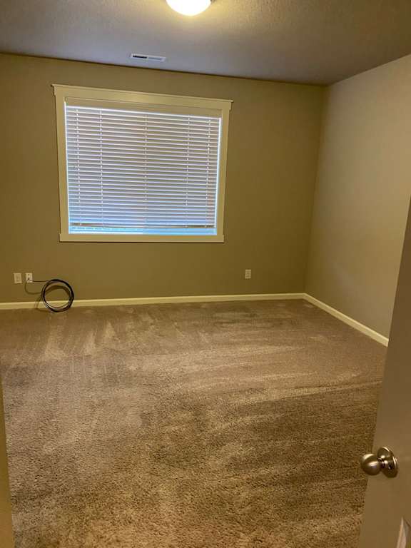an empty room with a window and carpet
