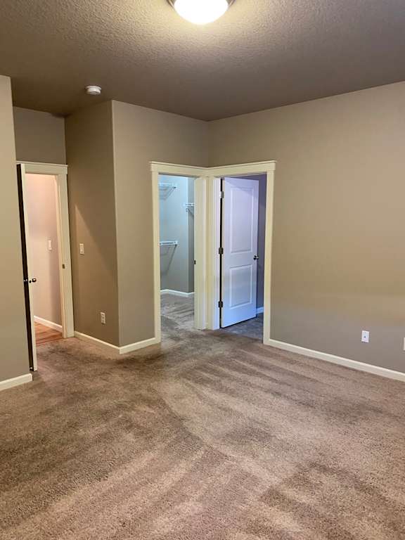 a bedroom with a carpeted floor and a doorway into a bathroom